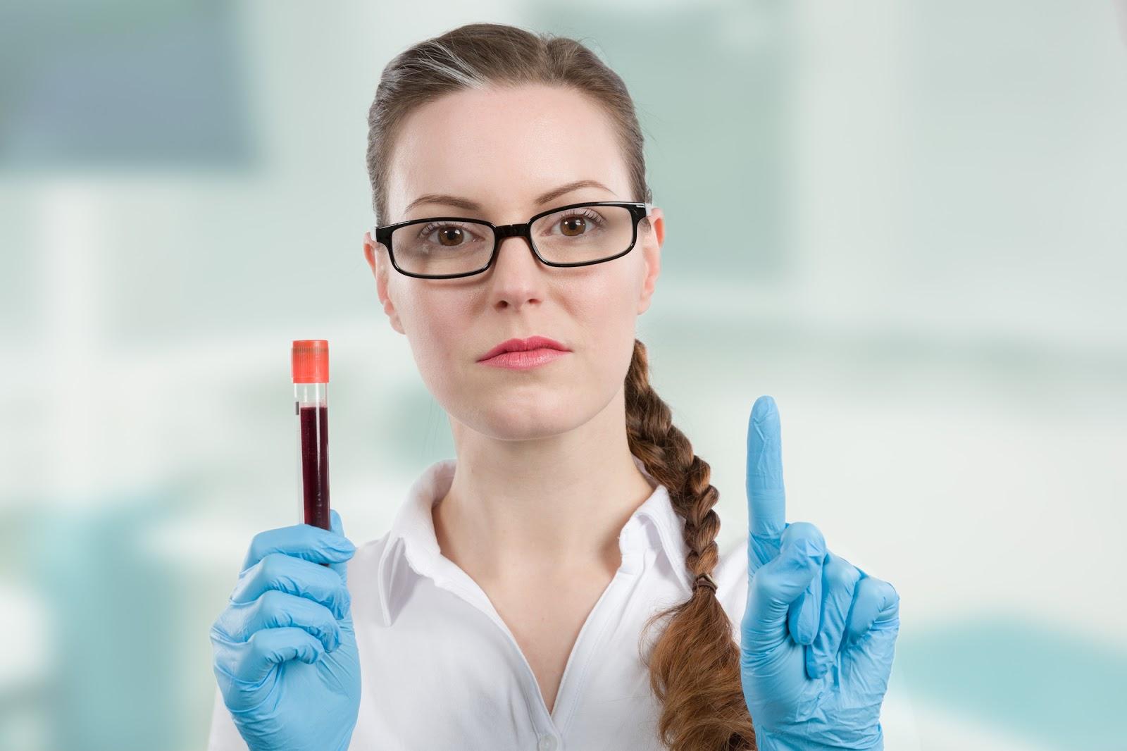 A young female doctor holds a laboratory blood tube filled with blood in one blue-gloved hand while holding up one finger on the other hand. There are many factors that can affect your blood alcohol level.