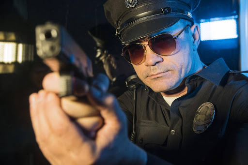 A white police officer points his gun. There are many types of police misconduct that may occur in a DWI case.