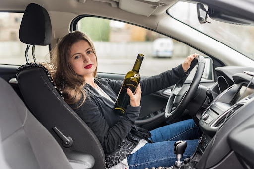 A young woman sits behind the wheel of a car with an empty wine bottle in her hand. How to expunge a DWI in New York may turn up disappointing results, but there are other options.